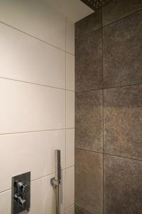 SchijndelPrachtig royaal gastenverblijf的浴室设有瓷砖墙和淋浴。