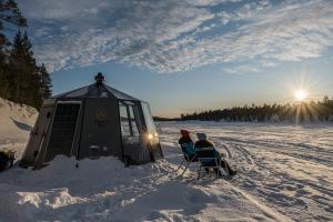 罗瓦涅米Aurora hut igloo的两个人坐在雪地里的椅子上