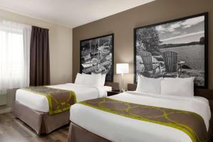 萨尼亚超级8萨尼亚酒店的酒店客房带两张床和一张桌子以及椅子。