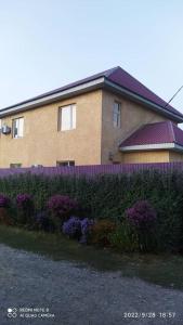 比什凯克Hotel "Тихий Дом Трансфер"的前面有栅栏和紫色花朵的房子