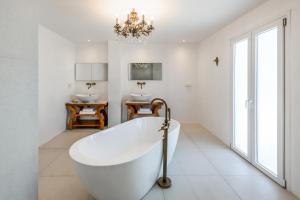 纳乌萨Kallisti Paros的带浴缸、两个盥洗盆和吊灯的浴室。