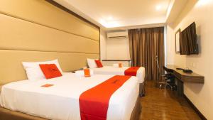 马尼拉RedDoorz Premium @ West Avenue Quezon City的酒店客房配有两张床和一张书桌