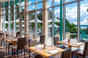 巴特萨罗皮斯库夫Precise Resort Bad Saarow - Golf & Spa的餐厅设有桌椅和大窗户。