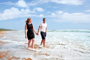 本托塔Centara Ceysands Resort & Spa Sri Lanka的站在海滩水面上的男人和女人