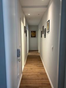 普里什蒂纳Ani’s apartment的走廊设有白色墙壁和木地板,墙上挂有图片