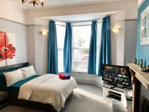 普里茅斯4Alma St的一间卧室配有蓝色窗帘、一张床和电视