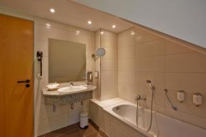 腓特烈罗达腓特烈罗达H+水疗酒店的浴室配有盥洗盆和浴缸。