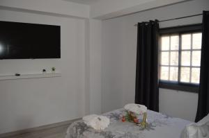 巴耶格兰雷伊瓜达乡村民宿的一间白色的房间,配有电视和一张带鲜花的桌子