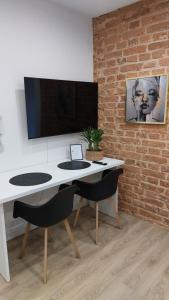 托伦Apartamenty K&B Toruń的一张带两把椅子的白色书桌和砖墙上的电视