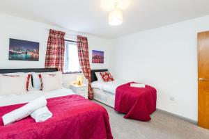 GoodmayesCosy 2 bedroom house! Dagenham! Free parking的一间卧室设有两张带红色床单的床和窗户。