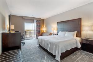 堪萨斯城Orangewood Inn & Suites Kansas City Airport的酒店客房设有一张大床和一个阳台。
