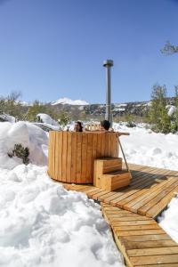拉斯特朗卡斯MI Lodge Las Trancas Hotel & Spa的两个人坐在雪地的木甲板上