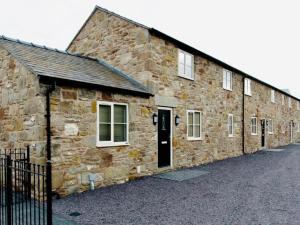 Connahs QuayConnah's Quay Park Farm Barns的一座古老的石头建筑,设有黑色的门和窗户