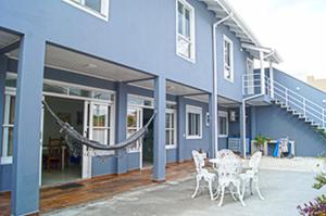帕罗卡Casa com 2 quartos à 200 m da da praia c/ churrasqueira的蓝色的建筑,前面设有桌椅