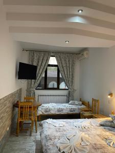 加布罗沃Guesthouse Hitar Petar的一间卧室设有两张床,墙上配有电视。