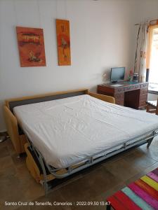 拉克鲁斯Schöne Wohnung in Puerto de la Cruz mit Garten.的一张位于带书桌和床架的房间的床铺