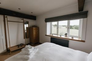 丹比戴尔BIRDS EDGE COTTAGE - Luxury 2 Bedroom Cottage with Amazing Views, Near Holmfirth in Yorkshire的卧室配有白色的床和窗户。