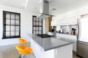 洛杉矶Urban Loft Apartment的厨房配有白色橱柜和橙色凳子
