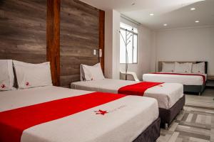 帕斯托Hotel Star Pasto的酒店客房带两张红色和白色的床单