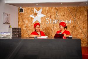帕斯托Hotel Star Pasto的两名穿着红色制服的女人坐在柜台