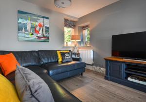 兰贝德罗格2 Bryn Hyfryd的客厅配有黑色真皮沙发和平面电视。