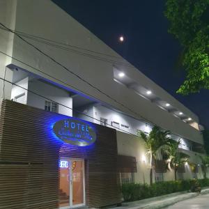 PalmasHotel Suites del Mar的上面有蓝色 ⁇ 虹灯标志的酒店大楼