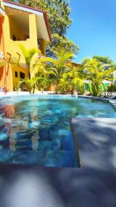 普拉亚弗拉明戈Hotel Tabasco的棕榈树建筑前的游泳池