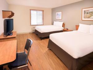 费耶特维尔Extended Stay America Select Suites - Fayetteville - Fort Bragg的酒店客房设有两张床、一张桌子和一台电视。