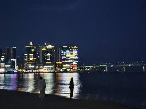 釜山JJ House Gwangan Beach的男人和女人晚上站在海滩上
