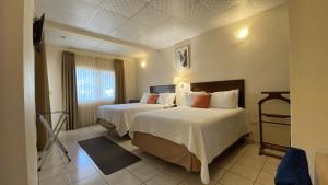 圣佩德罗苏拉Real Guanacaste的酒店客房设有两张床和窗户。