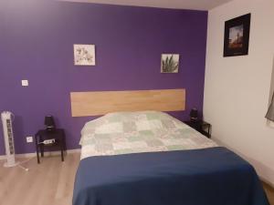 阿尔勒les papyrus avec draps的一间卧室配有一张紫色墙壁的床
