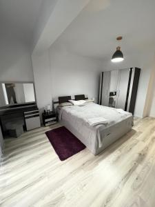 雅西Apartament de lux intr-o zona rezidentiala linistita的白色卧室设有一张大床和一架钢琴