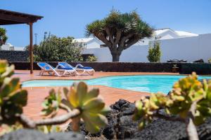 圣巴尔托洛梅Casa Lola Lanzarote piscina climatizada y wifi free的一个带两把椅子的游泳池,一个棕榈树