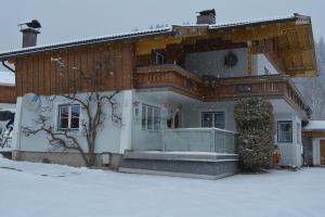 莱奥冈Gästehaus Huber的前面的地面上积雪的房子