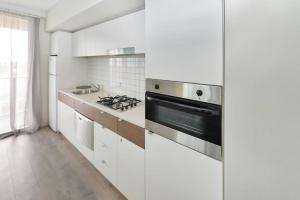 阿德莱德Light & Airy 3 Bd CBD Apt: BalconyTramWifi/Parking的厨房配有白色橱柜和炉灶烤箱。