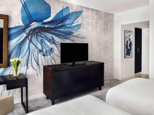 迪拜迪拜朱美拉湖塔楼瑞享酒店的一间带电视的卧室和一幅花画