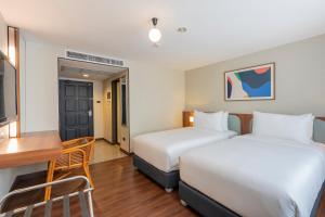曼谷Arck Hotel的酒店客房配有两张床和一张书桌