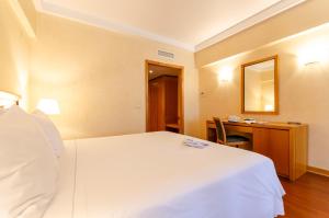 里斯本罗马酒店的一间酒店客房,配有一张白色的床和一张书桌