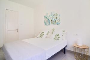 马拉加Villa Rosita Suites en Playa de la Malagueta con terraza的白色的卧室配有白色的床和墙上的绘画作品