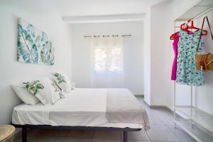 马拉加Villa Rosita Suites en Playa de la Malagueta con terraza的一间卧室,配有一张床,衣架上挂着一束衣服