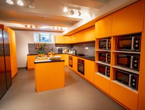 戛纳BANANA'S CAMP的橙色的厨房配有黑色家电和橱柜