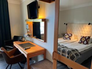 穆塔拉Hotell Östermalm的酒店客房带一张床、一张书桌和一面镜子