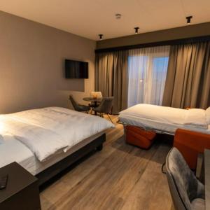 阿克雷里Hotel Halond的酒店客房带两张床和一张桌子以及椅子。