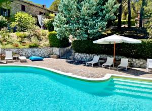 古比奥La Panoramica Gubbio - Maison de Charme - Casette e appartamenti self catering per vacanze meravigliose!的游泳池配有椅子、遮阳伞和遮阳伞