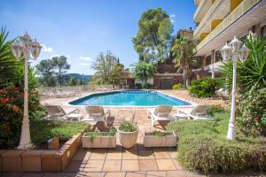 科贝拉罗布里加Can Fisa Hotel & Apartments的一座带椅子的庭院和一座建筑中的游泳池