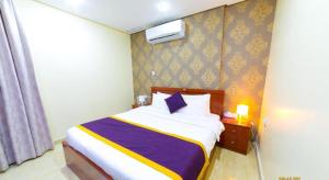 科威特Relax inn Apartment - Fahaheel的一间卧室配有一张带紫色和黄色毯子的床