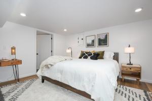 温哥华Bright & Modern Basement Apartment Dt N'hood的白色卧室配有一张大床和两盏灯。