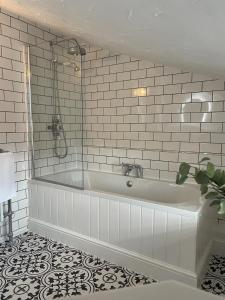 威灵顿Worlington Hall的浴室铺有白色瓷砖,配有浴缸。