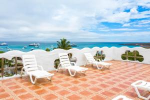 巴克里索莫雷诺港Royal Galápagos Inn的庭院里摆放着一组白色椅子,
