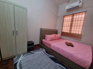 史里肯邦安D’Lestari Homestay的卧室配有粉红色的床和窗户。